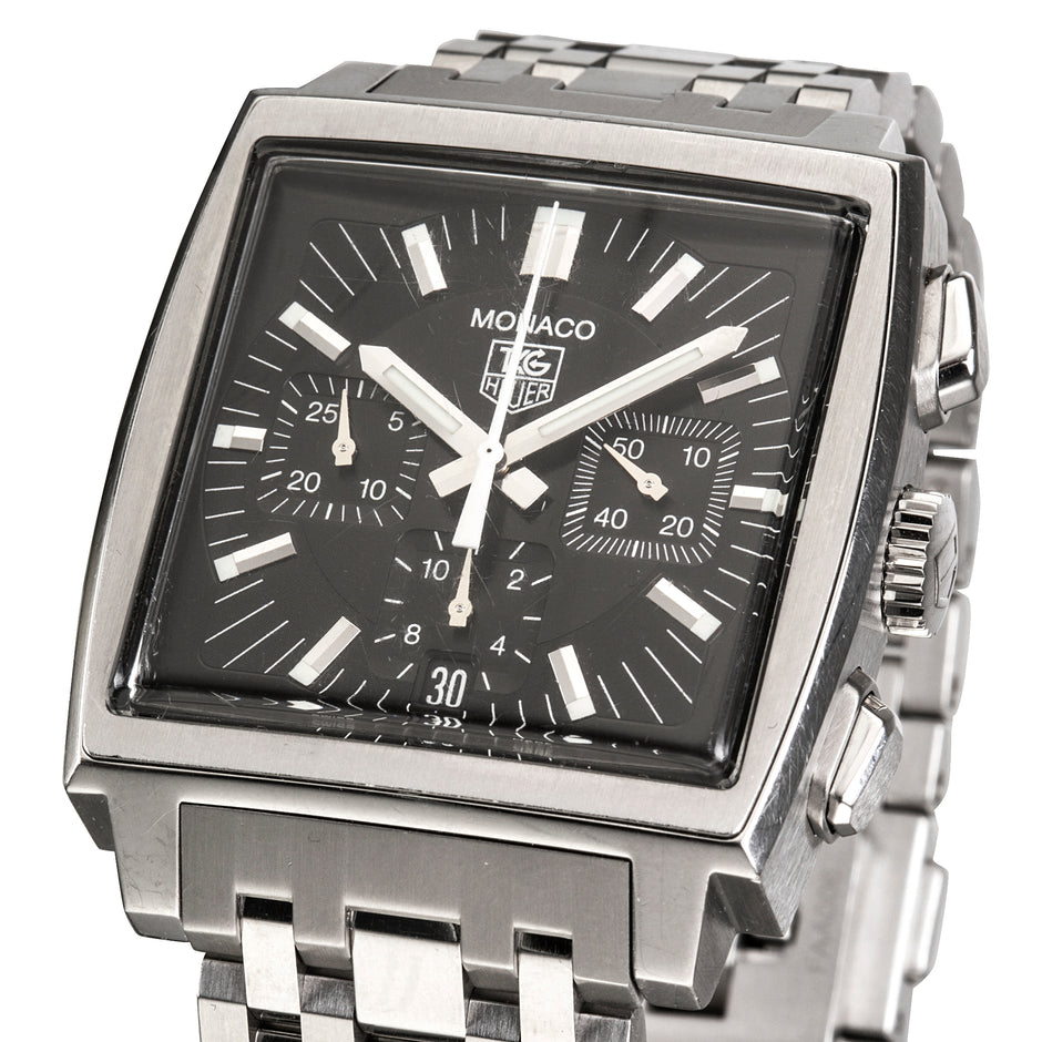 A Tag Heuer Monaco watch with a square stainless steel case, black dial, and matching steel link bracelet, shown on a white background.