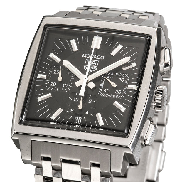 A Tag Heuer Monaco watch with a square stainless steel case, black dial, and matching steel link bracelet, shown on a white background.