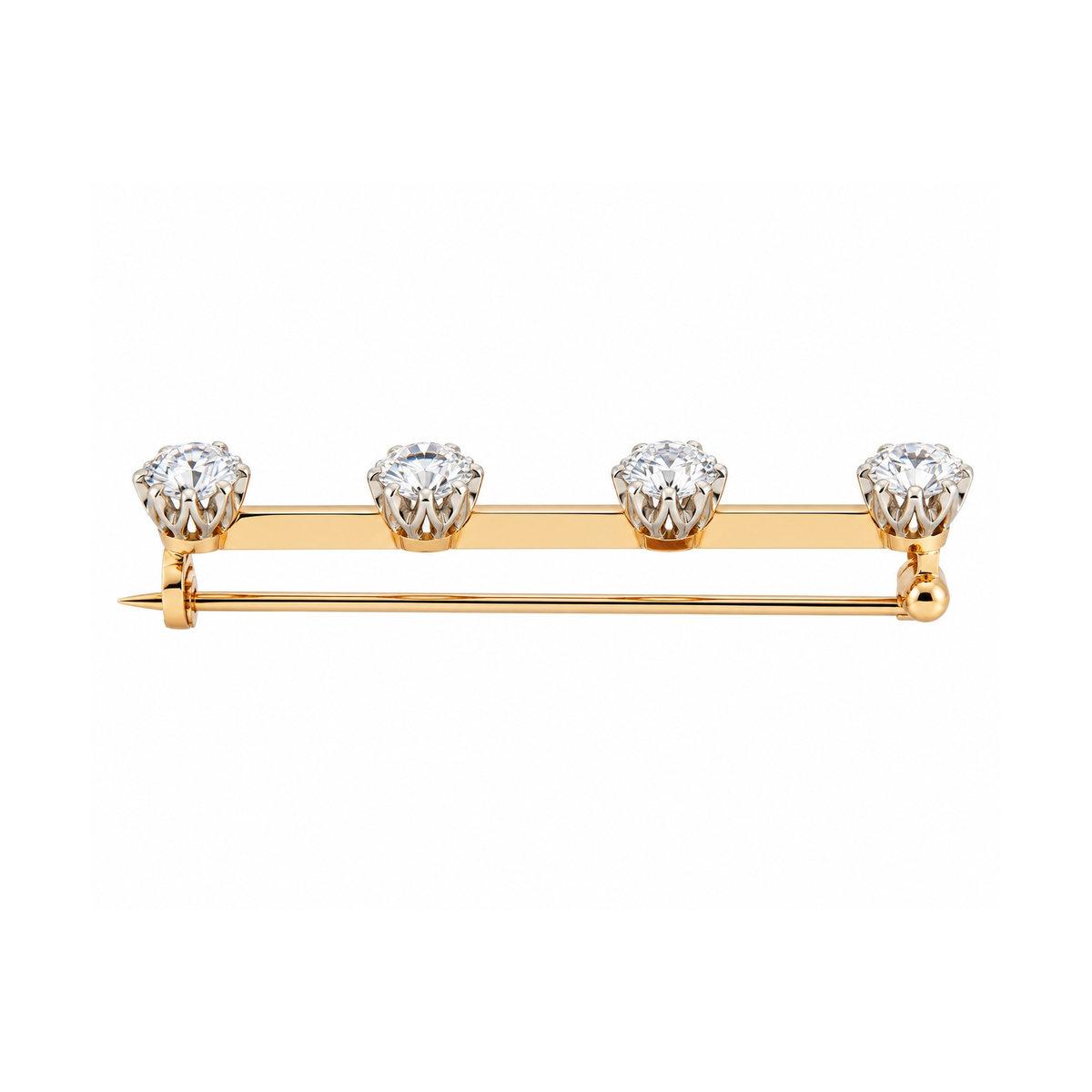 A yellow and rose gold bar pin featuring four round-cut clear gemstones set in a row, photographed on a solid white background.