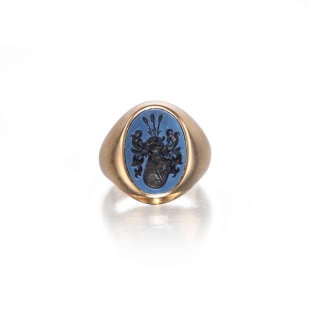 Gold ring with a blue stone and black engraved design on a white background