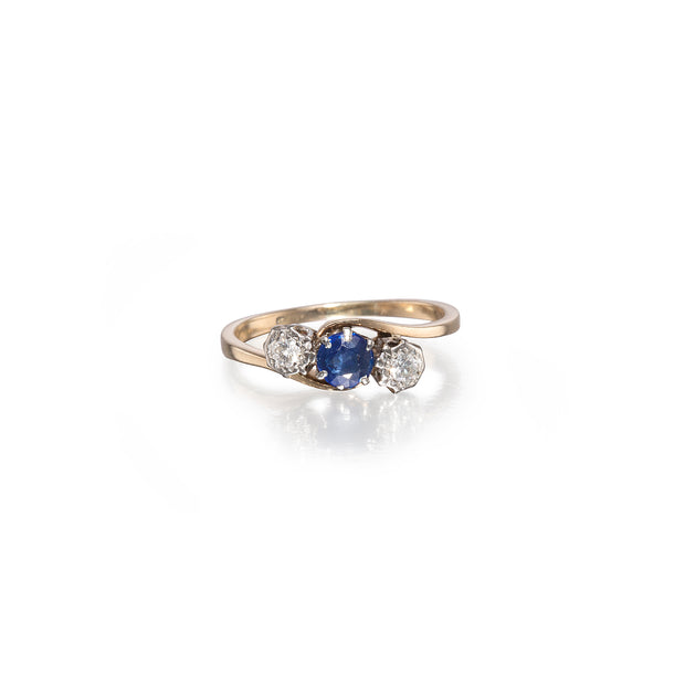 Gold ring with a blue gemstone and two diamonds on a white background