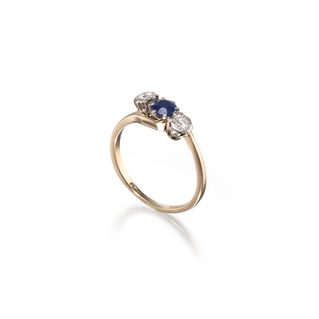 Gold ring with a blue gemstone and diamonds on a white background