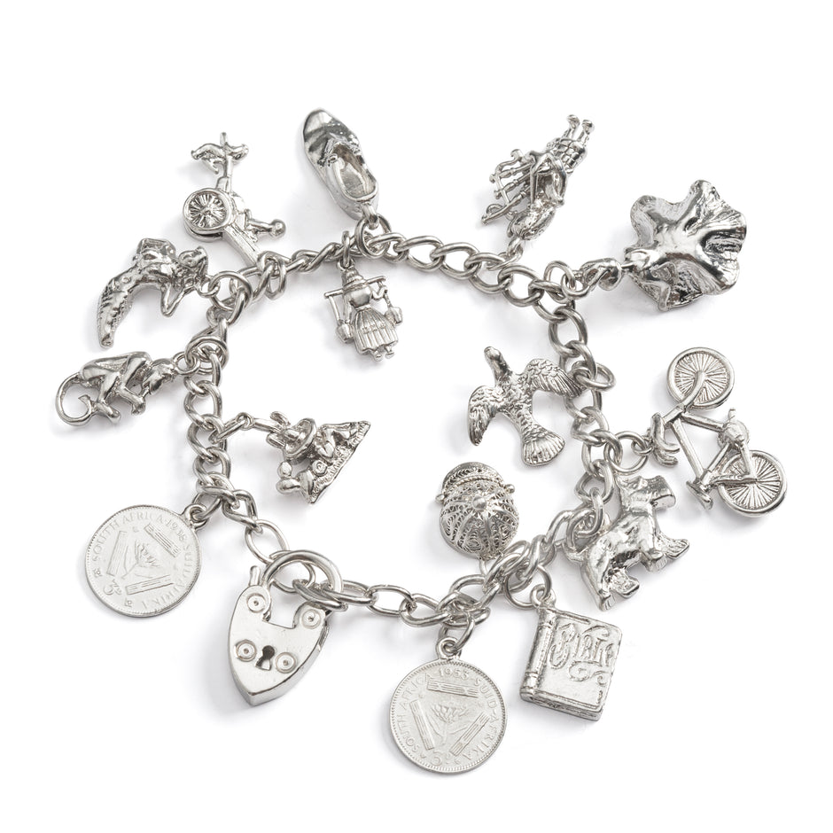 Silver charm bracelet with various charms on a white background