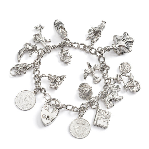 Silver charm bracelet with various charms on a white background