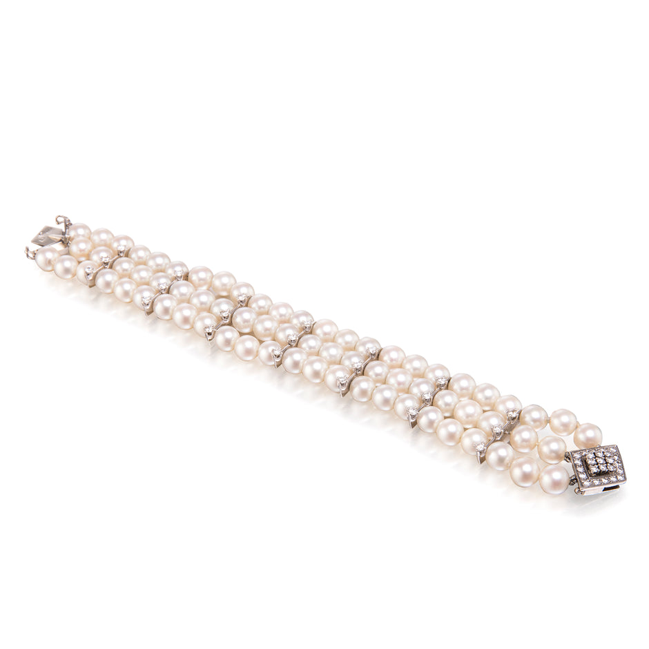 Three-strand pearl bracelet with a silver clasp on a white background