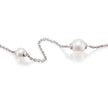 A white gold chain necklace featuring two white freshwater pearls, one larger pearl on the right and one smaller pearl on the left, both set in silver bezels, displayed on a clean white background with soft reflections.